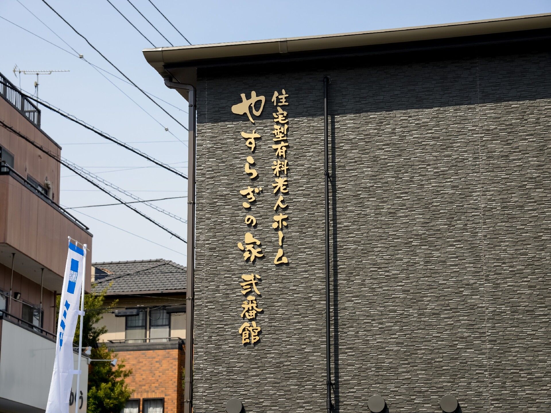こちらを向いて笑顔になる車いすの高齢女性と介護施設の女性スタッフの様子
