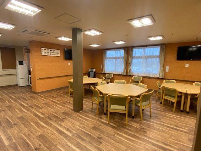 車いすに乗った女性を押す家族の男性とそこに寄り添う介護スタッフの様子