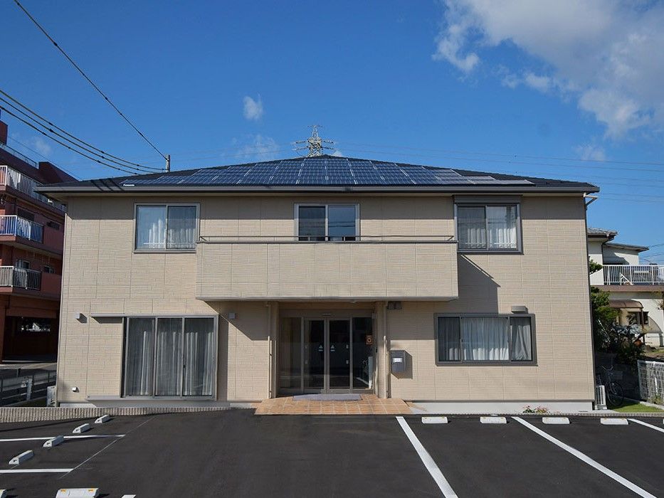 茶色い壁と三角屋根、バルコニーがある2階建ての建物