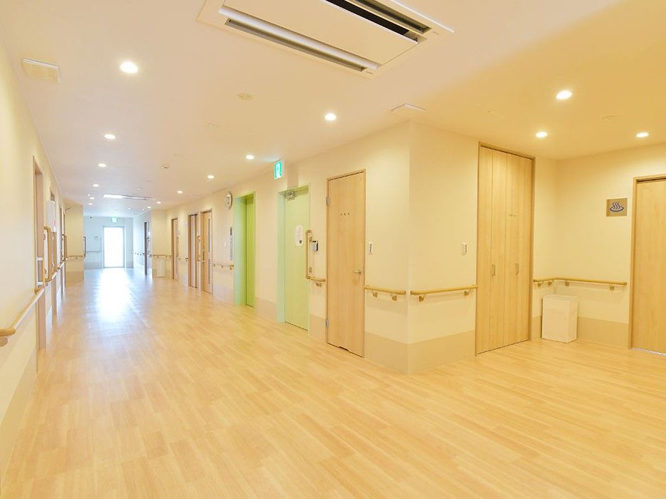 広々とした廊下をはさんで、グリーンとベージュ、2色のドアの部屋が複数並んでいる空間