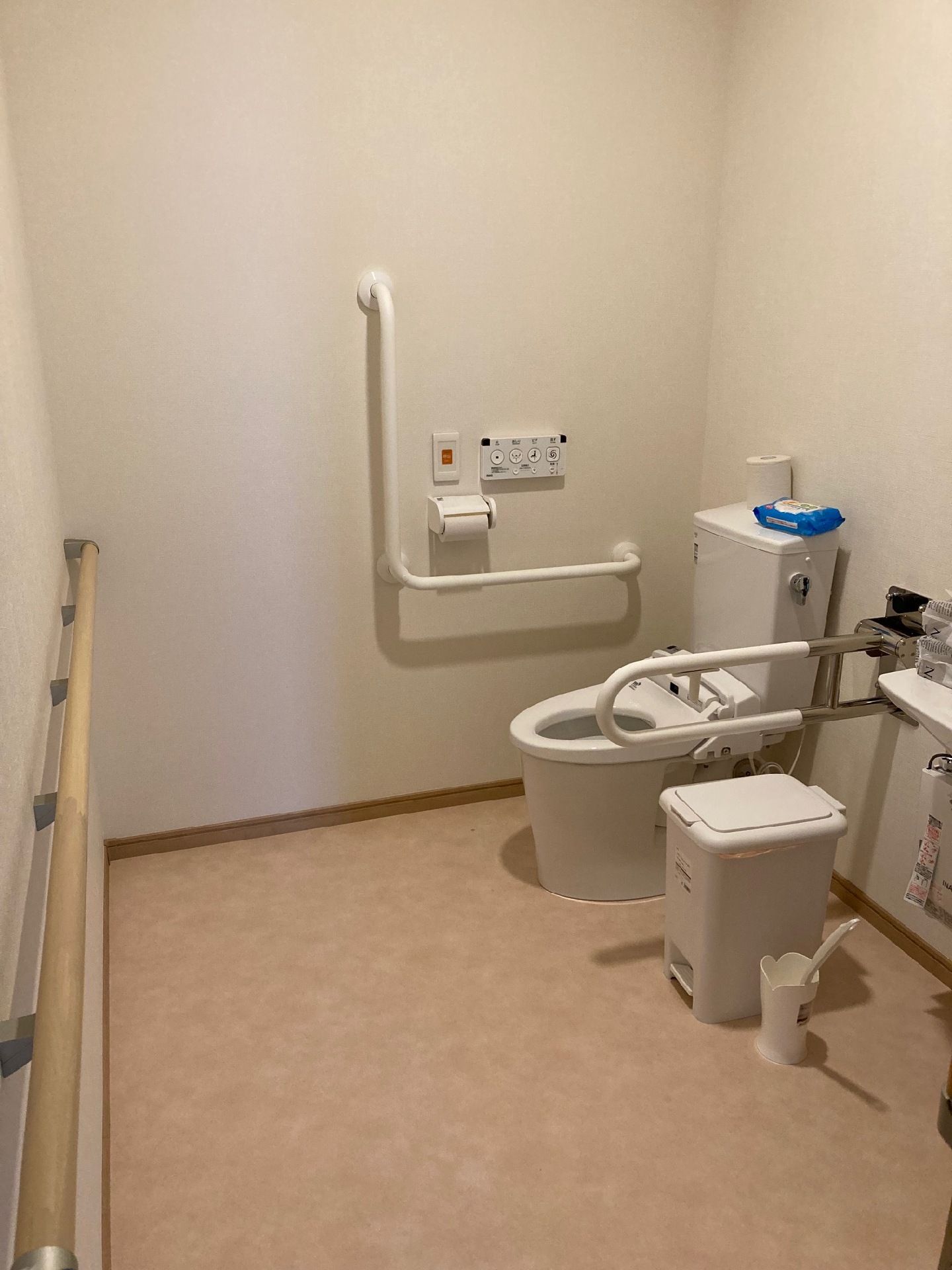 広いトイレにはたくさんの手すりがあり、便座にはふたがない。オレンジの呼び出しボタンも付いている。
