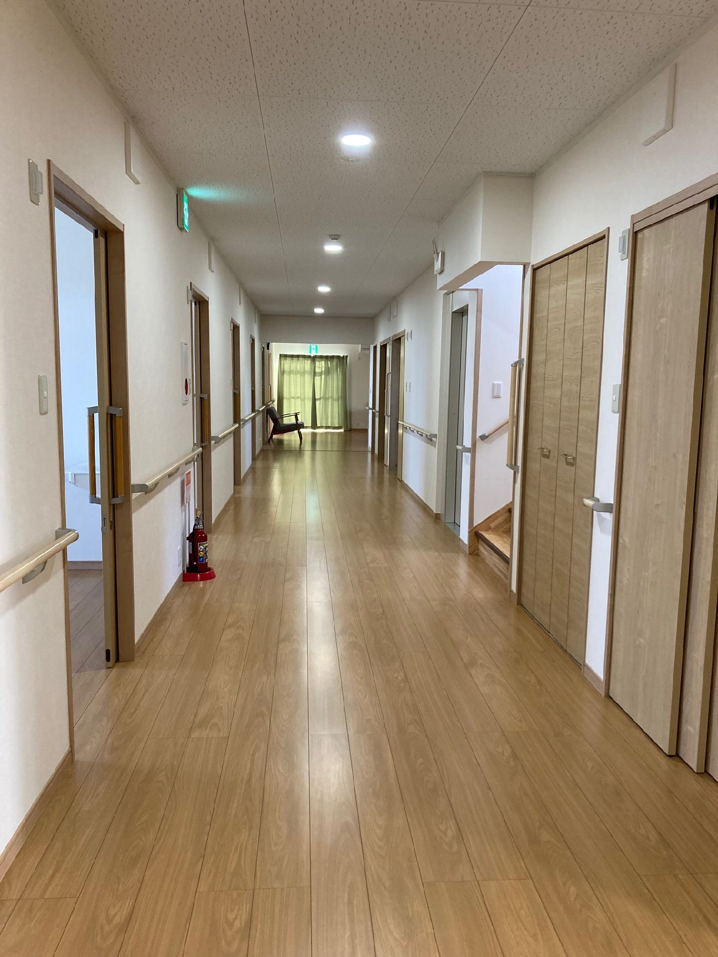 スライド式のドアが付いた居室が並ぶまっすぐな廊下の両サイドに手すりが設置され、歩行の邪魔になるものは置かれていない。