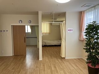 右側のカーテンで開け閉めするタイプの部屋の横には「静養室」と書かれた紙が貼られ、左側には居室がある。