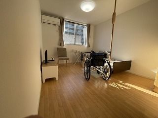 介護ベッドやエアコン、車いす、テレビなどが置かれたフローリングの居室には窓もある。