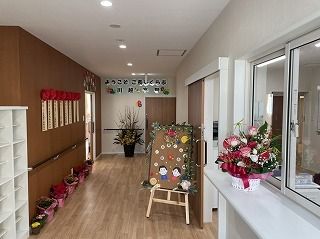 右側には花が飾られた受付があり、左側には靴箱があり、壁には手すりが付き、ウエルカムボードもある。