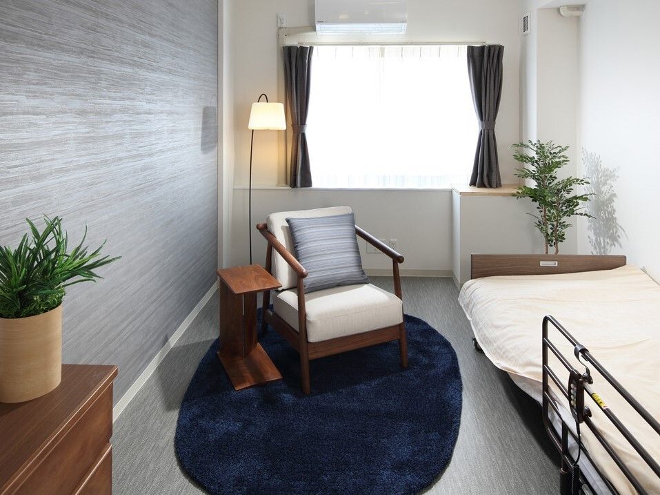 カーテンが付いた窓がある部屋には寝具付きのベッドやタンス、一人用の椅子、エアコンなどがある。