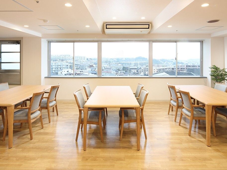 4人掛けのダイニングテーブルセットが複数置かれているフローリングの食堂には大きな窓が付いている。