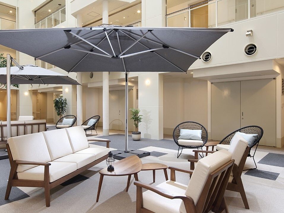 大きなパラソルが付いたテーブルセットが複数置かれている。あちこちに観葉植物が置かれ、明るい雰囲気。