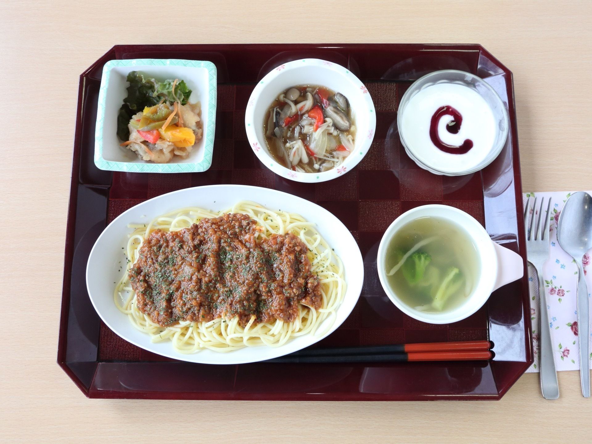 ある日の給食のメニュー。スパゲティーミートソース、コンソメスープ、和え物、野菜の煮びたし、ヨーグルトである。