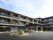 3階建ての建物はブラウン系でエル字型。日当たりのいい場所に建っていて、広い駐車場もある。