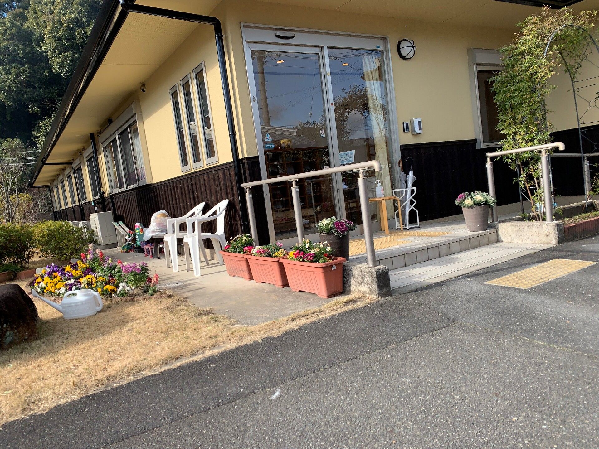 車いすの高齢者と手を握りながら話す介護スタッフの様子。施設内での会話の場面