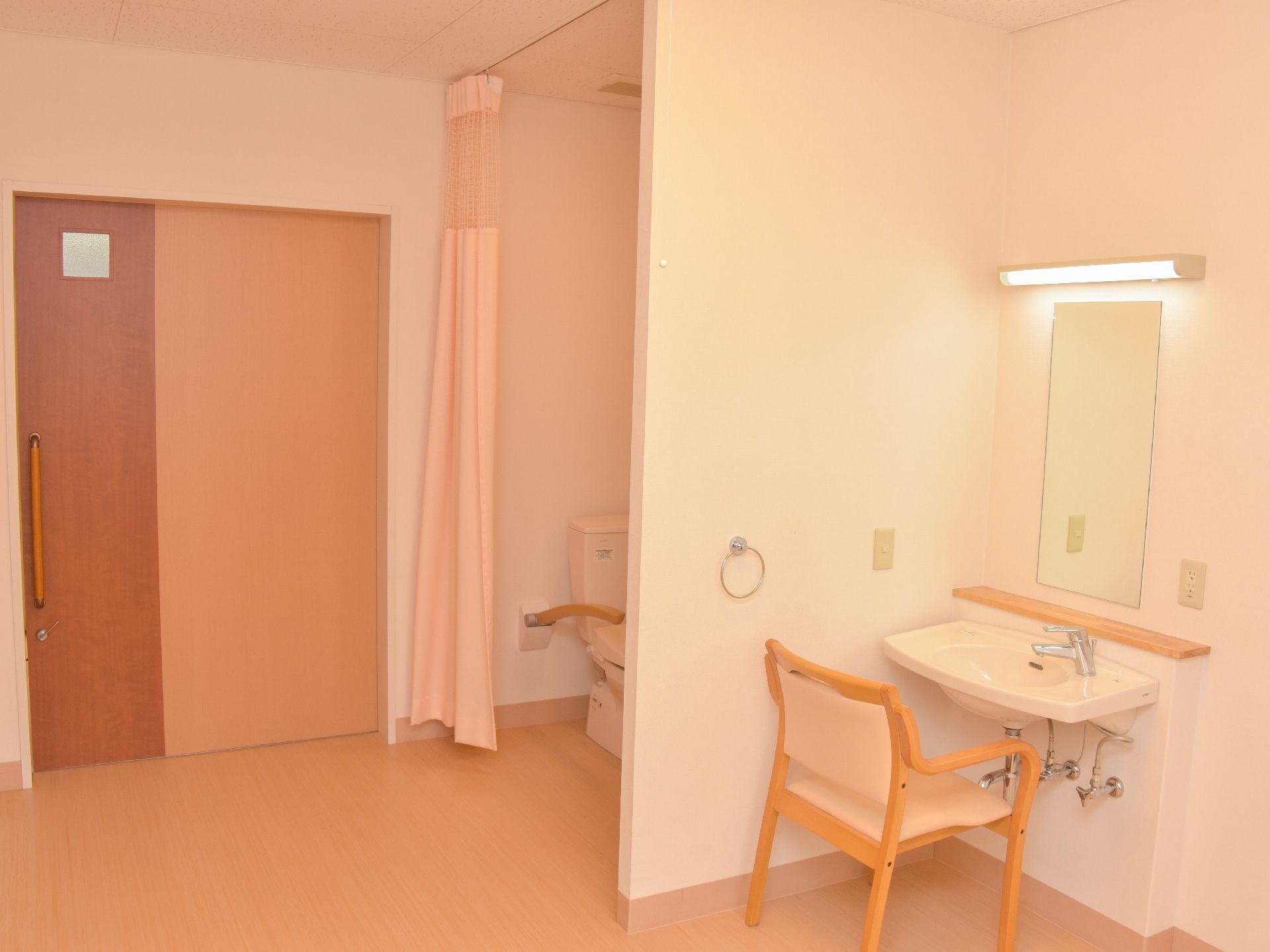 カーテンで仕切られた、出入りしやすいトイレが設置された居室