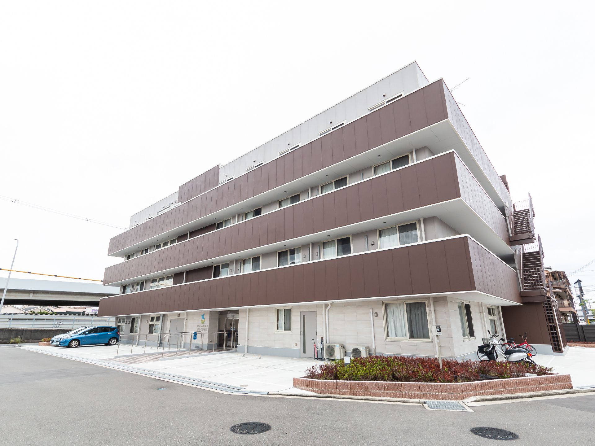 水の入ったコップを持ったエプロンを付けた女性スタッフが薬を飲もうとしている高齢女性のそばで微笑んでいる。