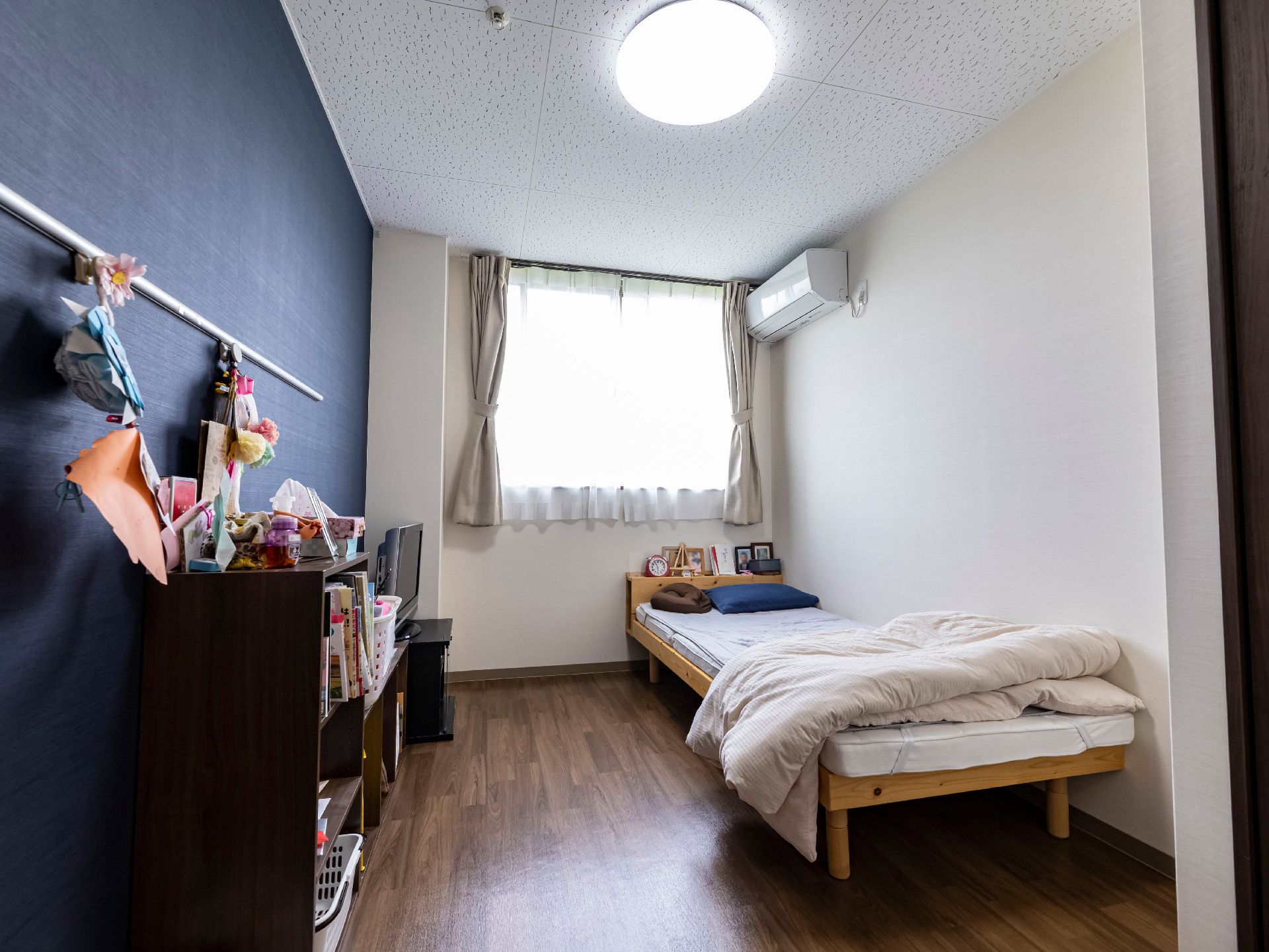 なにかを見て笑顔で手をたたいている高齢女性とスタッフの様子。施設での一場面の写真