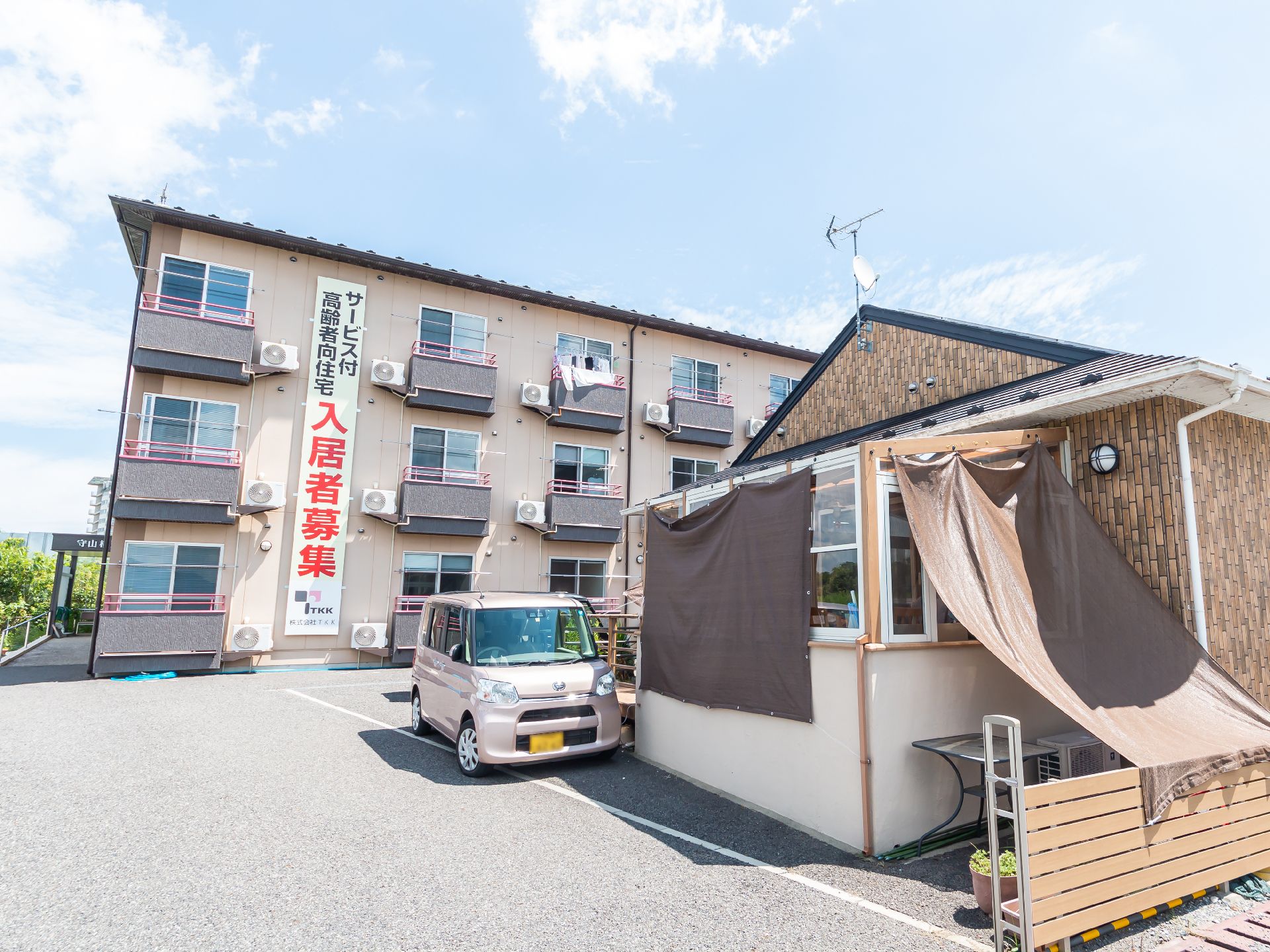 アスファルトに隣接した３階建てでベージュの外観の建物
