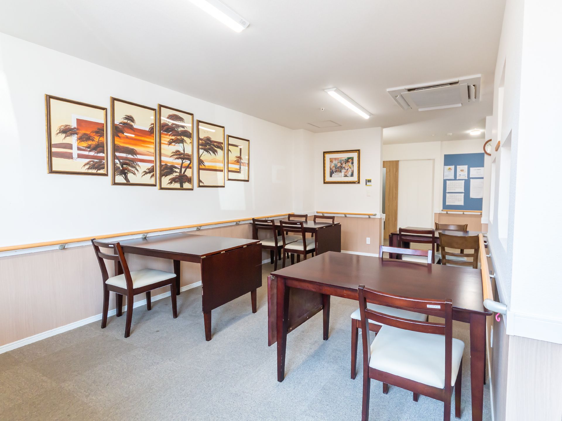 木製の机と椅子が並んでいる白い壁の部屋