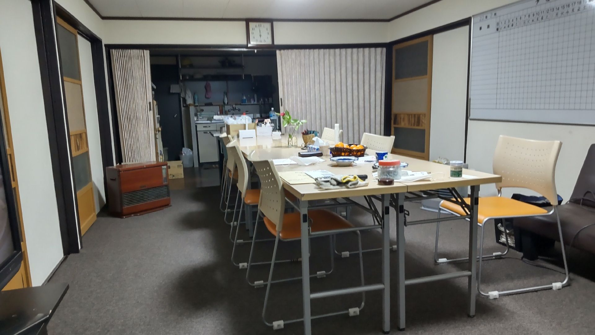 屋外で若い男女のスタッフに囲まれた笑顔で過ごしている車いすの高齢女性と付き添いの高齢男性。