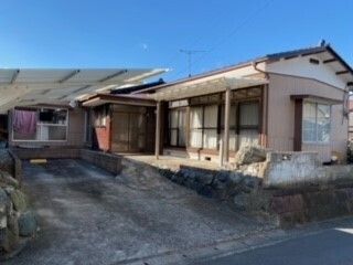 ベンチが置かれた玄関には屋根がある、オレンジの外壁の平屋建ての建物。車も止められている。