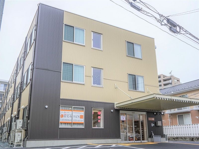笑顔でこちらを向いている施設のスタッフと車いすに乗っている高齢者の様子。施設で写された写真
