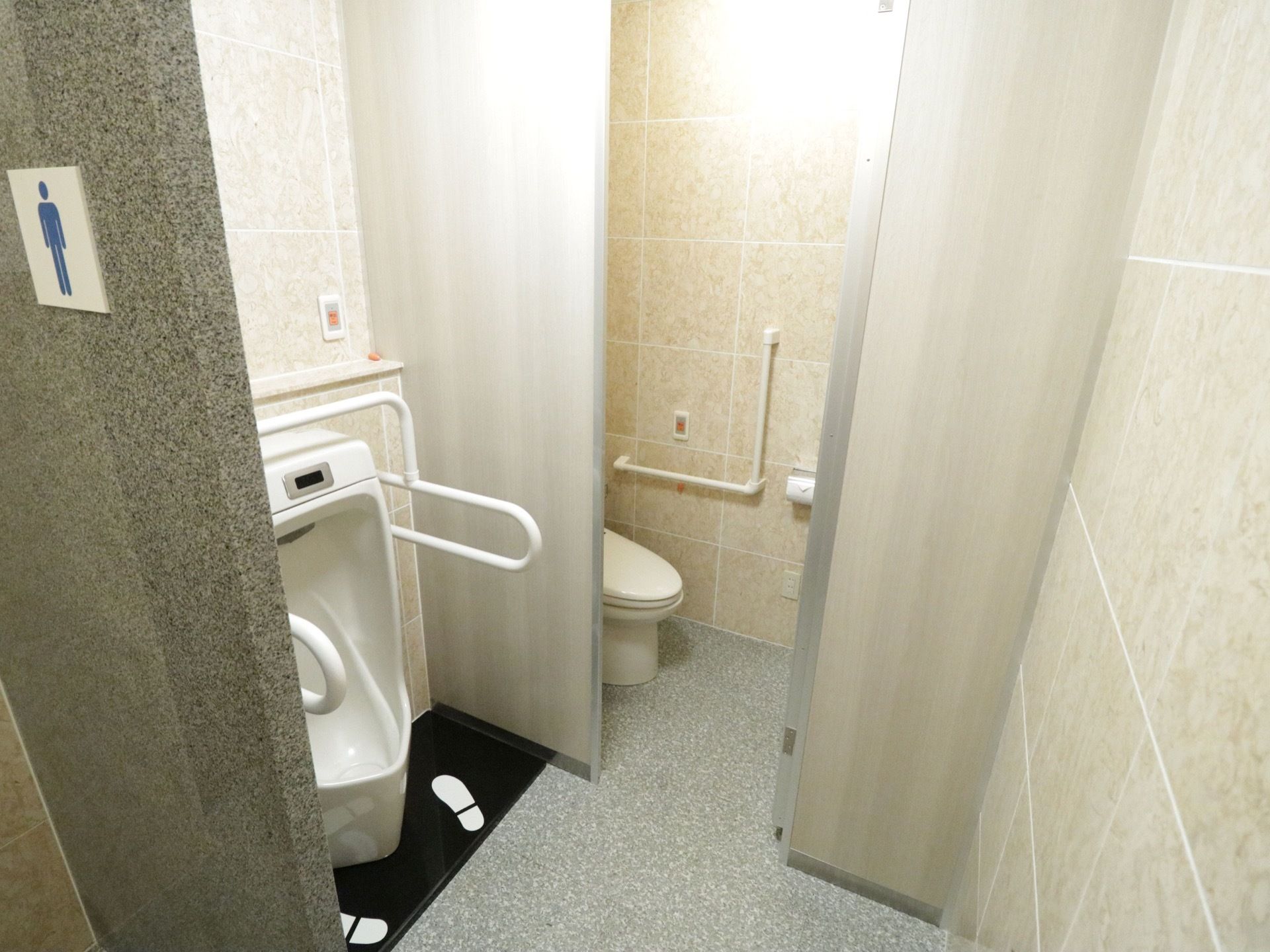 清潔感のある清掃の行き届いた男性用の共有トイレである。温水洗浄便座と小便用の便器の両方が備わっている。