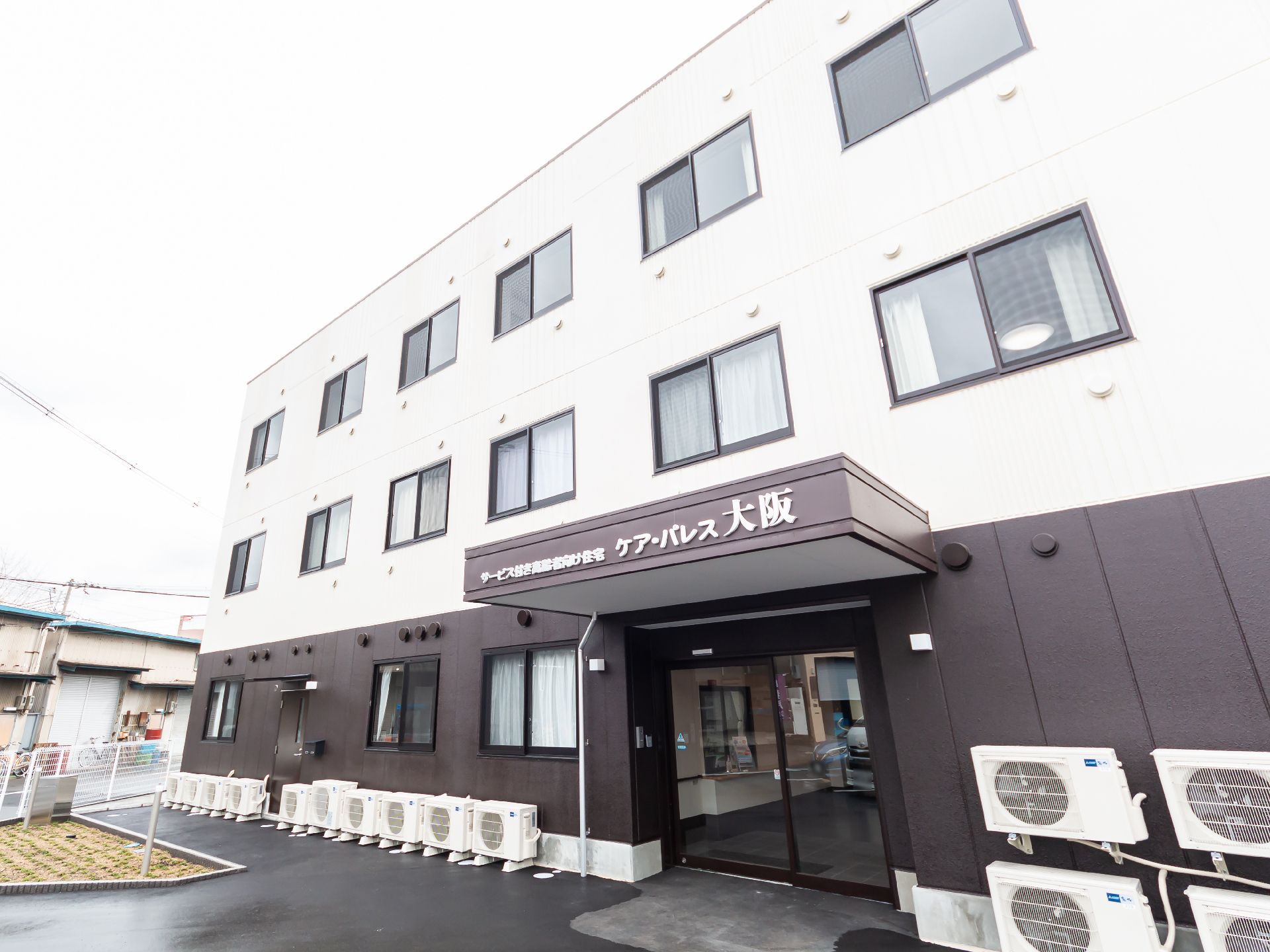 車いすに乗った女性を押す家族の男性とそこに寄り添う介護スタッフの様子