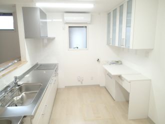 白を基調としたキッチン内には車いす対応の作業台やIHクッキングヒーターが付いていて、収納もある。
