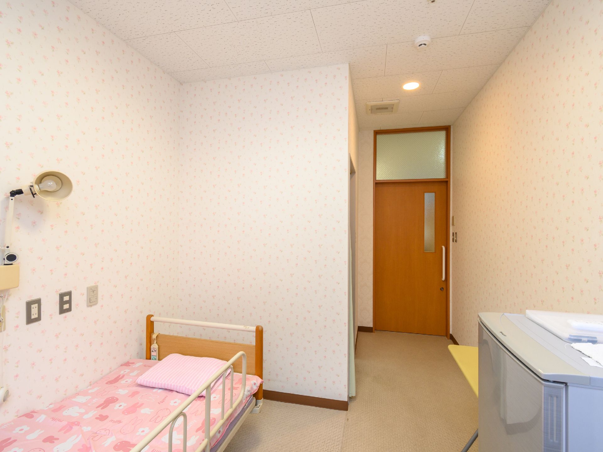 カメラに向かって笑顔を見せるスタッフと高齢者の女性。施設での何気ない一場面の様子