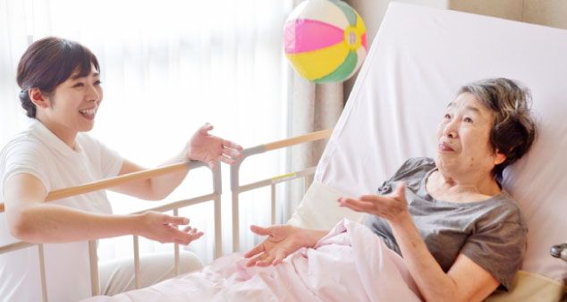 介護ベッドに横になる女性とケアワーカー