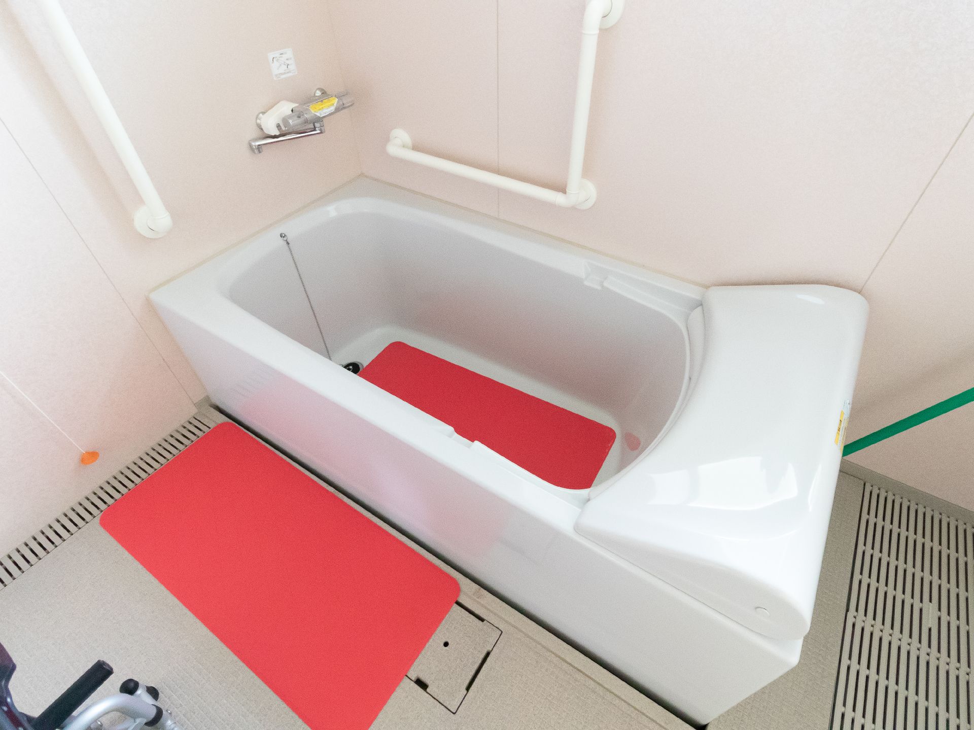 白い壁の一角に置かれた赤いマットレスが敷かれた白い浴槽