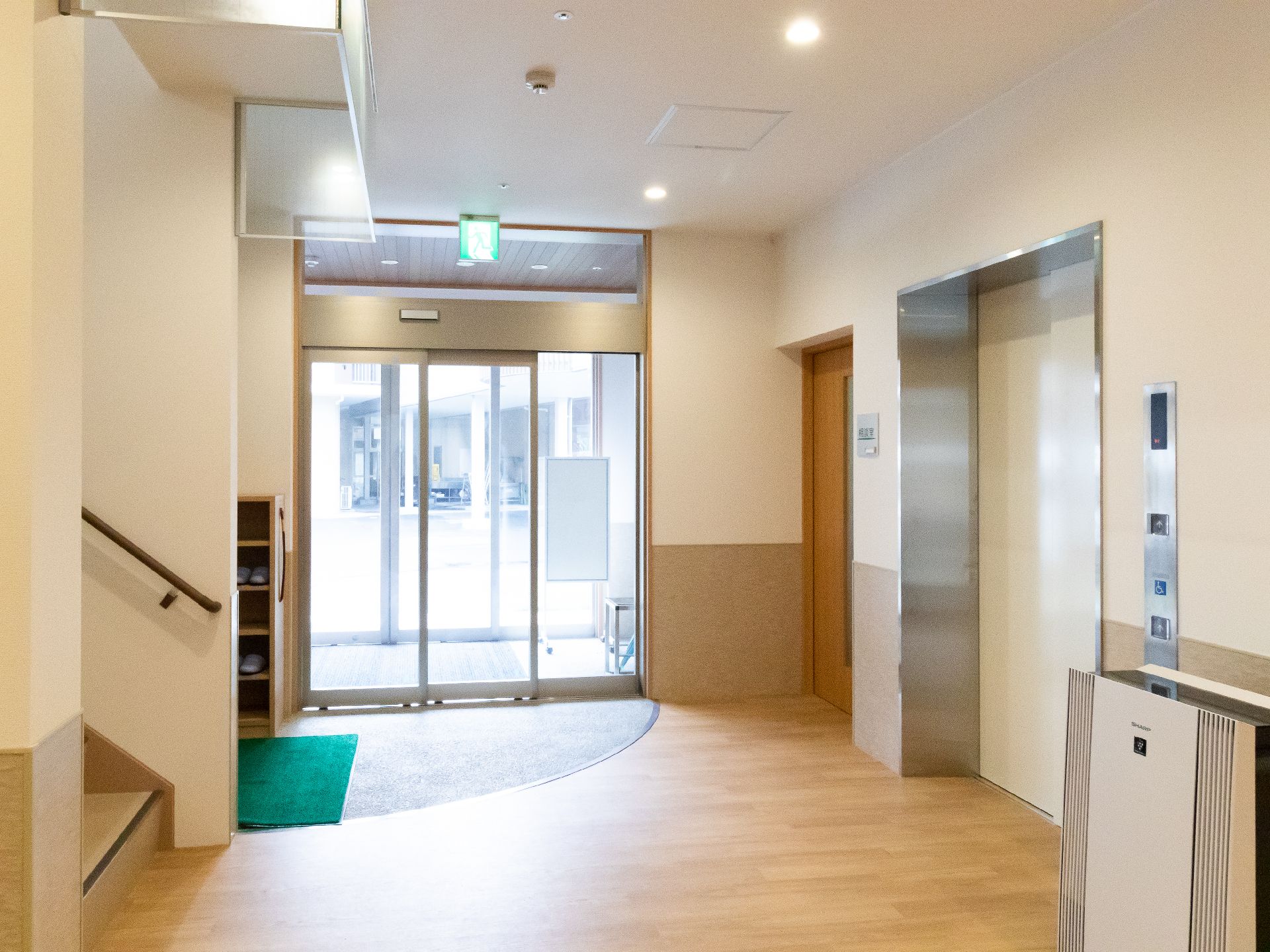 エレベーターと階段が両脇にある建物の自動ドアがあるエントランス