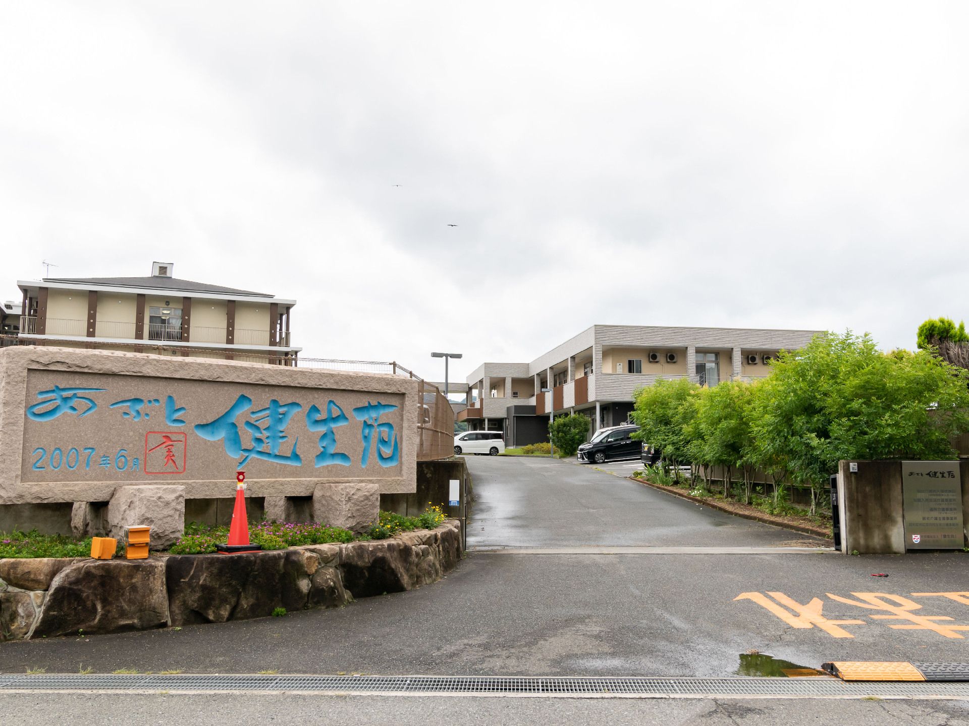 奥に建物と車が見えるアスファルトの道路から伸びた坂道