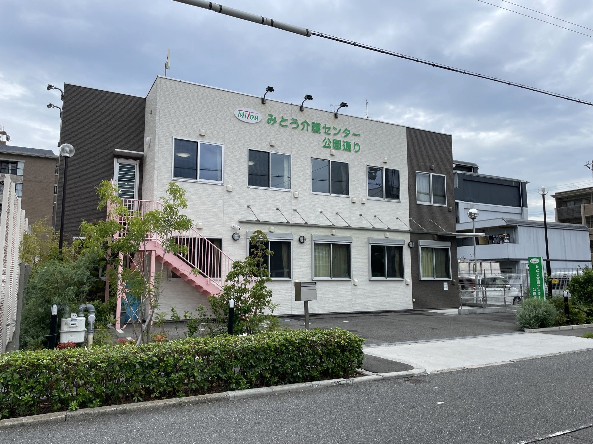 2階建ての建物にピンク色の階段がある施設