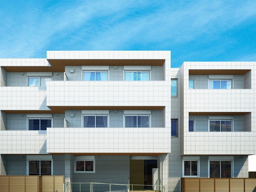 各フロアにベランダがある3階建ての建物は白を基調としていて、玄関には手すり付きのスロープがある。