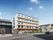 5階建ての建物は白を基調としていて、ベランダがブラウン。建物の前には駐車スペースもある。
