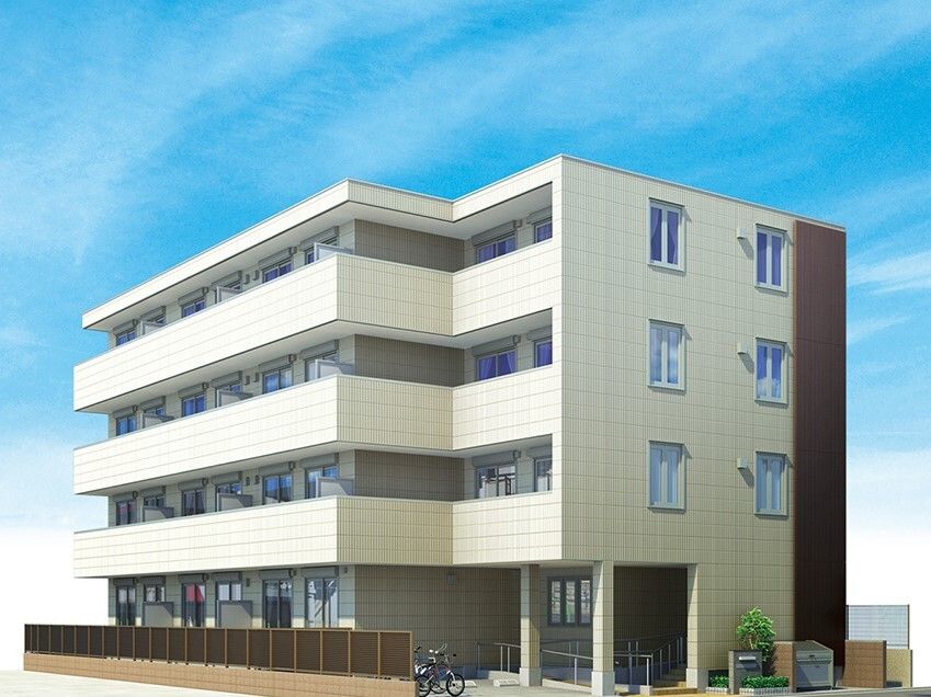 4階建ての建物は玄関には手すり付きのスロープがあり、各フロアにベランダがあり、1階部分には目隠しとなるフェンスもある。