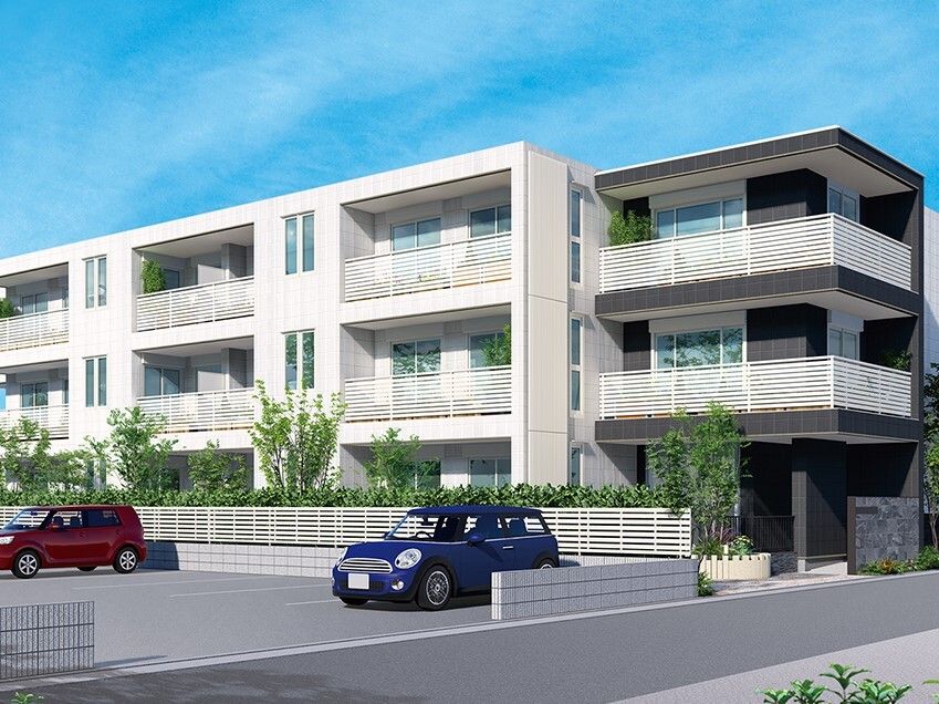 広い駐車場が付いた3階建ての建物の周りには草木が植えられ、白を基調としたすっきりとしたデザイン。