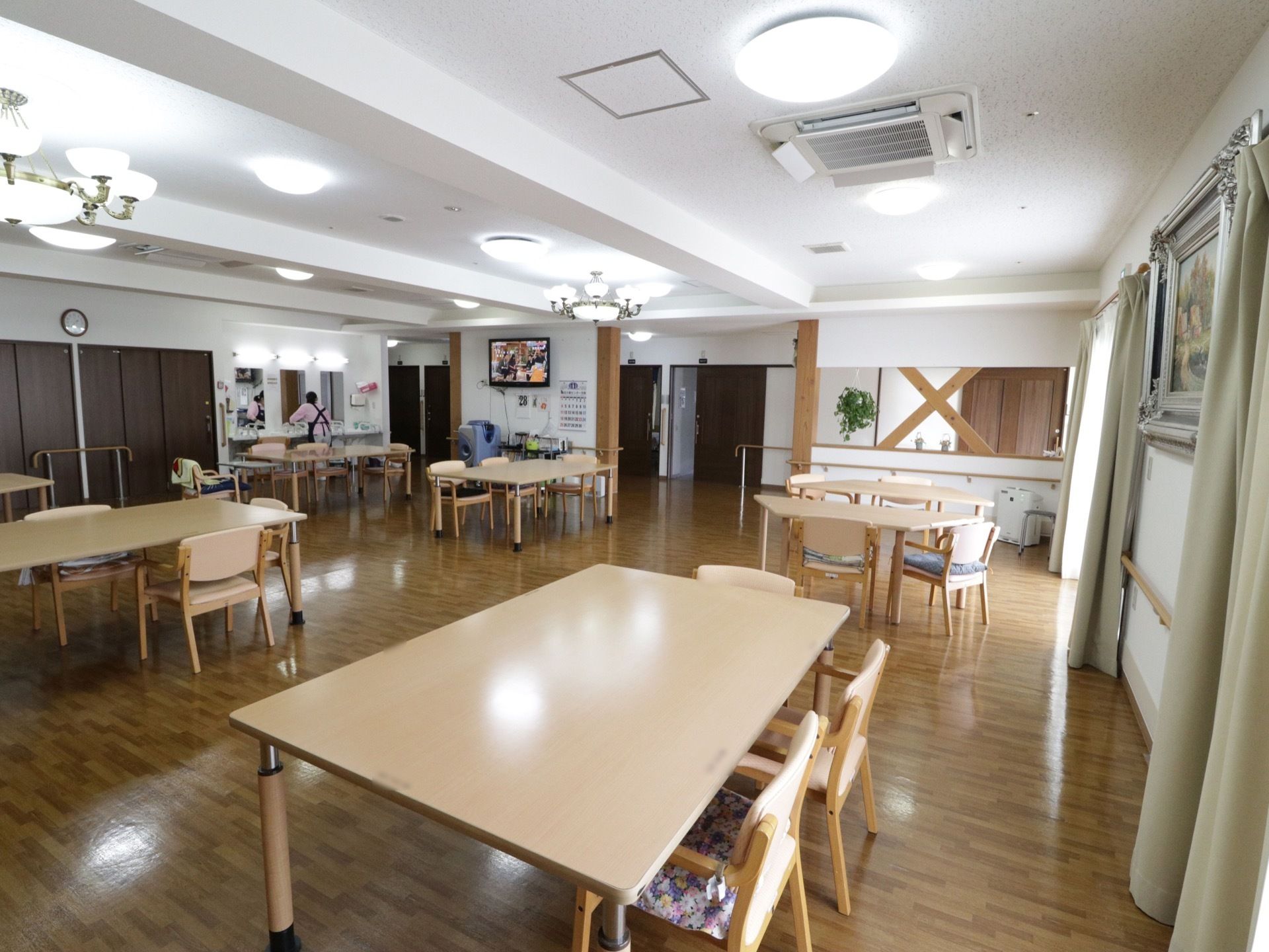 広々とした食堂である。木製のダイニングテーブルが並べられており、左奥の壁際に洗面スペースが設けられている。
