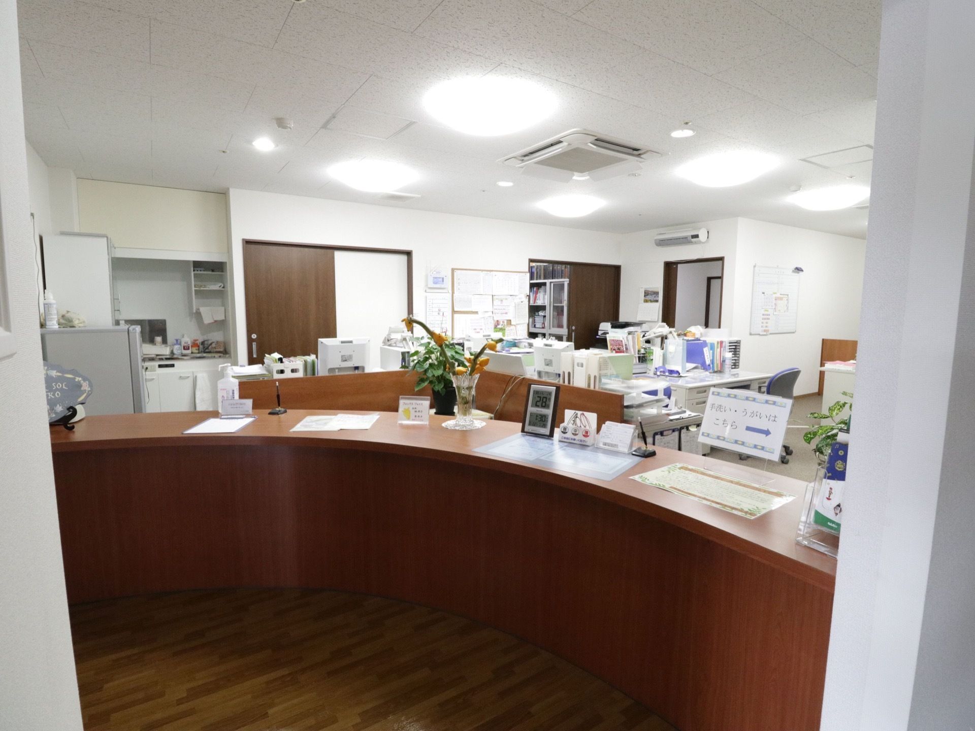 ヘルパーステーションは広く明るい部屋である。手前にカウンターが設置されており、時計や花瓶が置かれている。