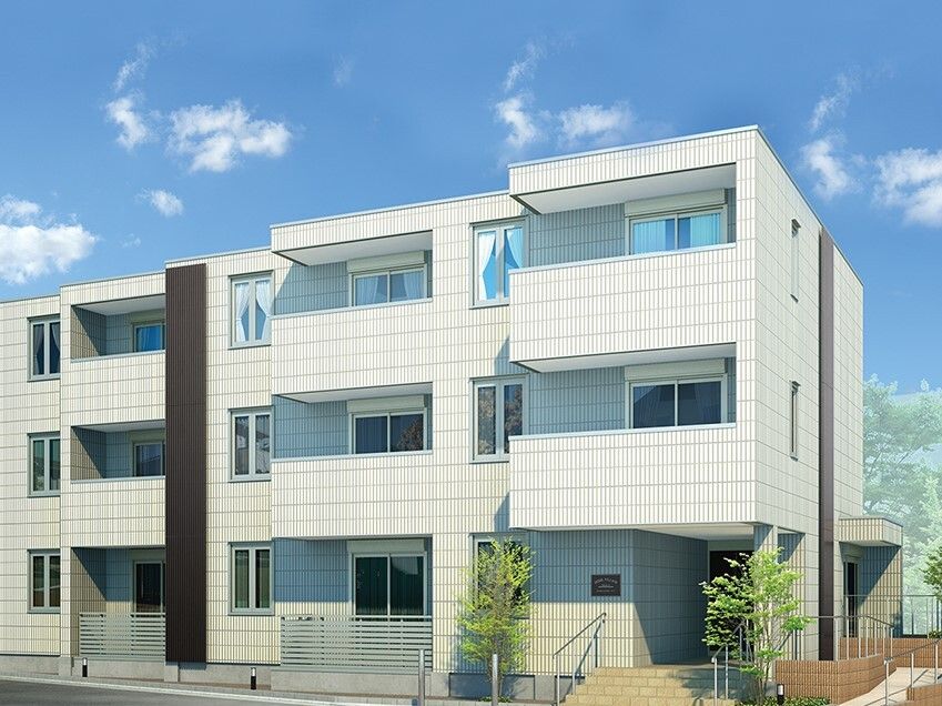 白を基調とした3階建ての建物。各フロアにベランダがあり、玄関先には手すり付きの階段とスロープが設置されている。