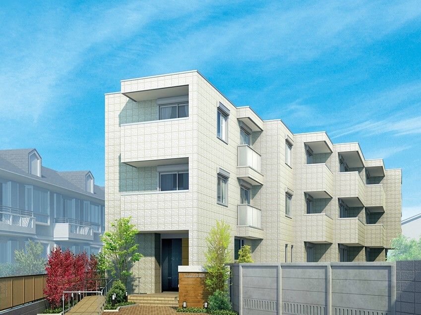 白を基調とした3階建ての建物。波打つような形状の建物で入り口付近には草木が植えられている。
