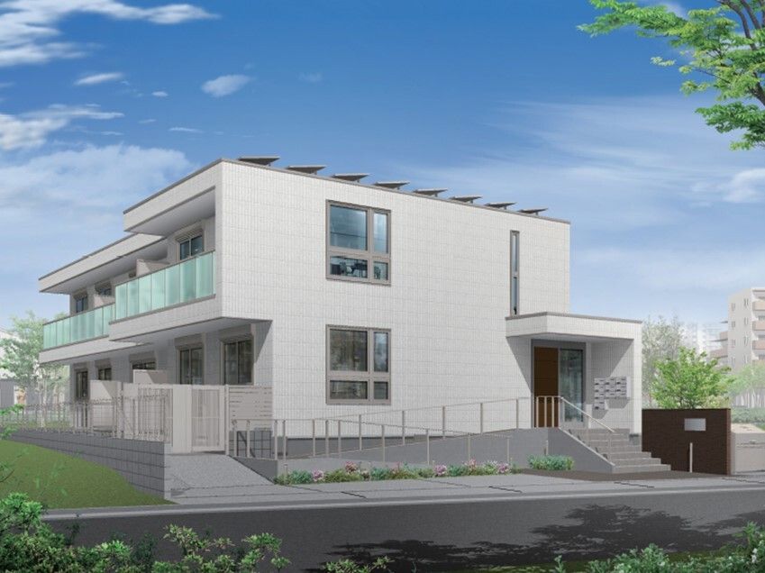 白を基調とした２階建ての建物。ベランダが付き、周りには緑が多く残っていて、玄関には手すり付きのスロープと階段が付いている。