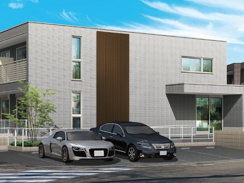 建物の前に駐車場があり、車が数台止められている。グレー系の2階建ての建物にはベランダもある。