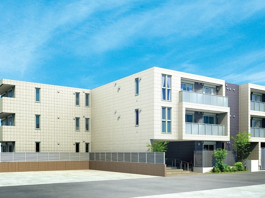 白を基調とした3階建ての建物は中央部分が飛び出ていて、玄関には階段と手すり付きのスロープがあり、駐車場もある。