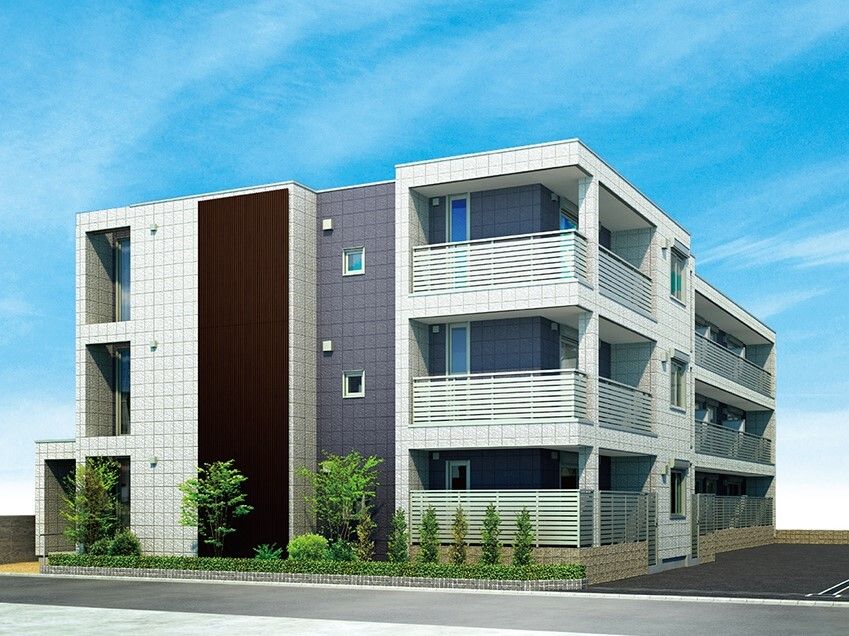 白を基調とした3階建ての建物は各フロアにベランダがあり、周りには草木が植えられ、駐車場もある。