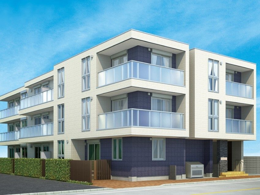 白を基調とした3階建ての建物。１階部分はダークグレーで生垣もあり、各フロアにベランダがある。