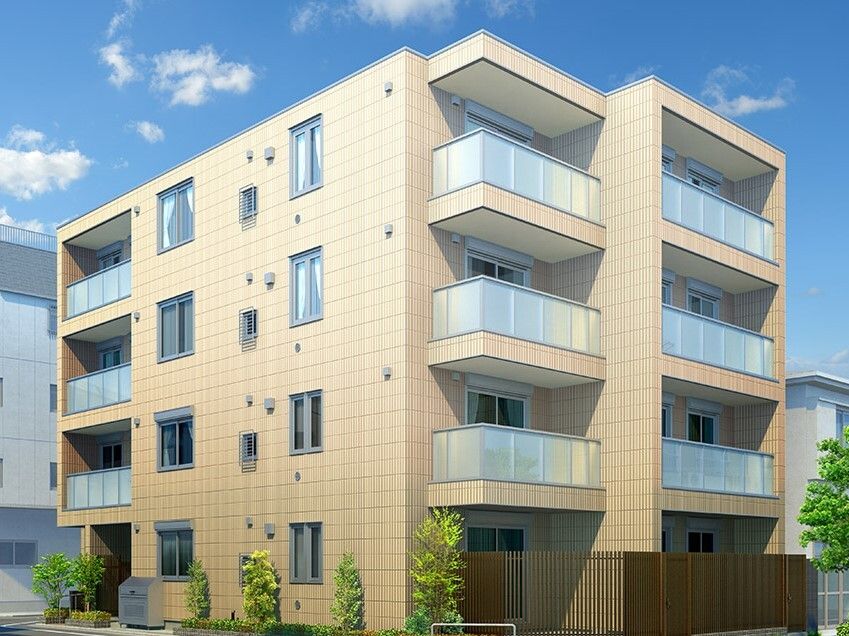 各フロアにベランダがある4階建ての建物はベージュ系で周りには草木が植えられている。周囲にも建物がある。