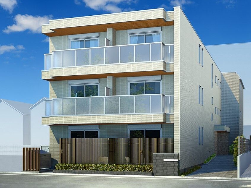 3階建ての建物の周りには草木が植えられ、門には住宅名が書かれている。ベージュの建物にはベランダが付いている。