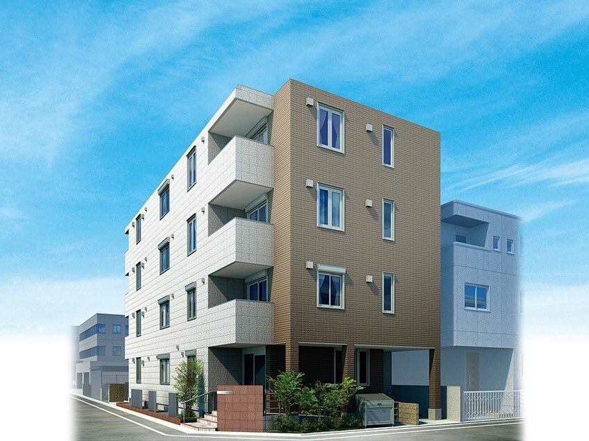 白とブラウンの3階建ての建物の周りには草木が植えられていて、周りにも建物がある。