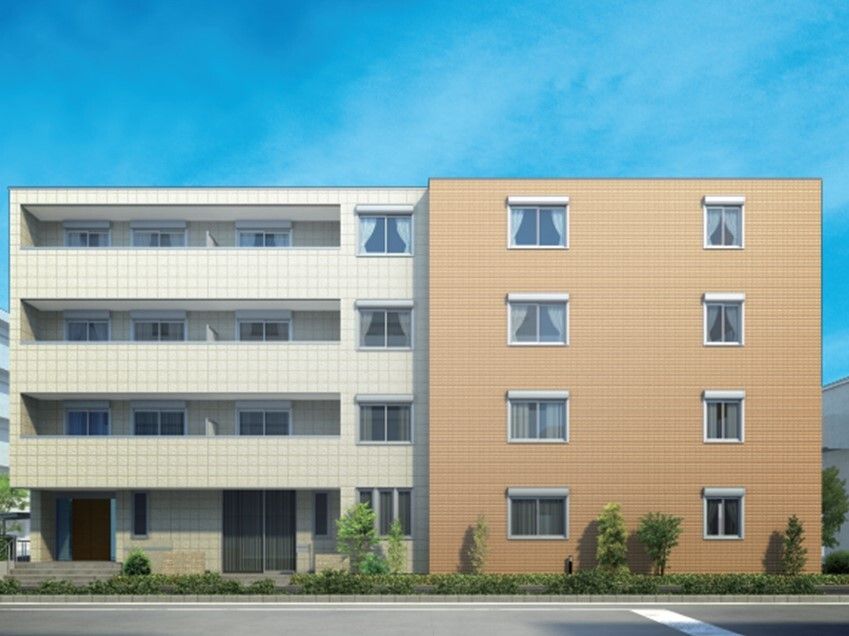 4階建ての建物は白とブラウンで各フロアにベランダがあり、周りには草木が植えられている。