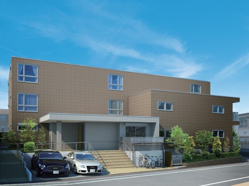 日当たりのいい場所に建っているブラウン系の3階建ての建物の前には駐車場と駐輪場が設置されている。